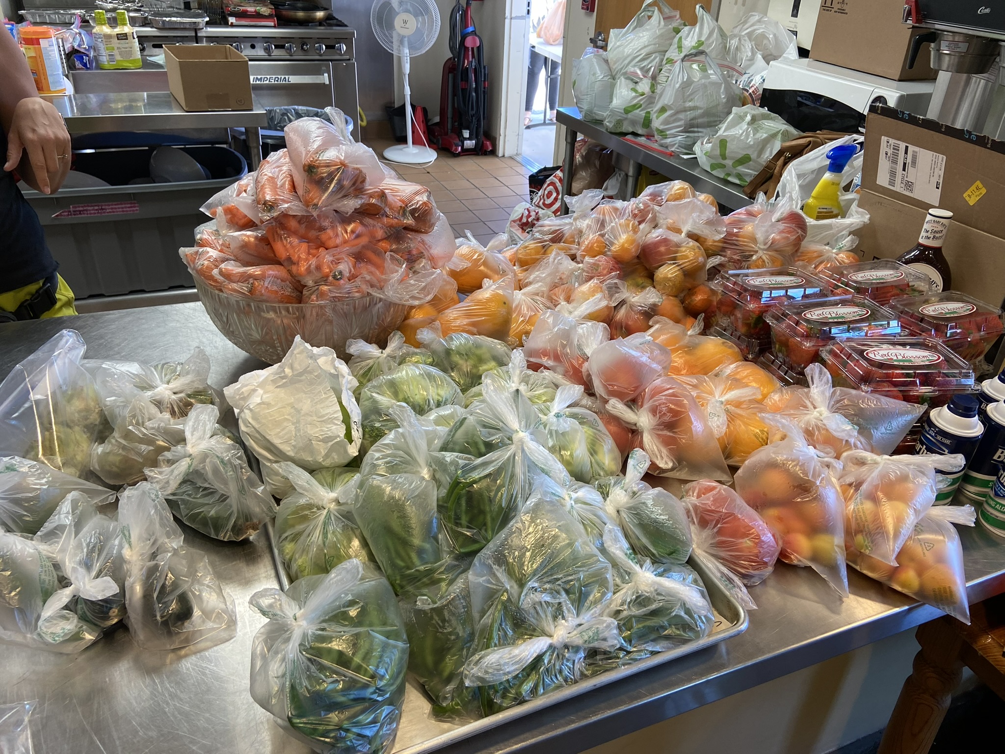 Bags of carrots, oranges, strawberries and greens sorted on the prep counter